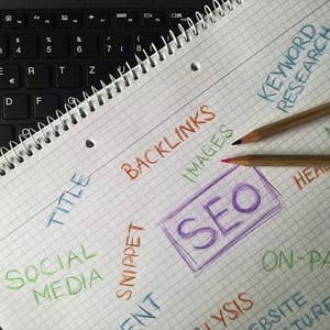 Notedpad with a pencil. There is writing on the notepad relating to SEO, social media and other digital marketing facets.
